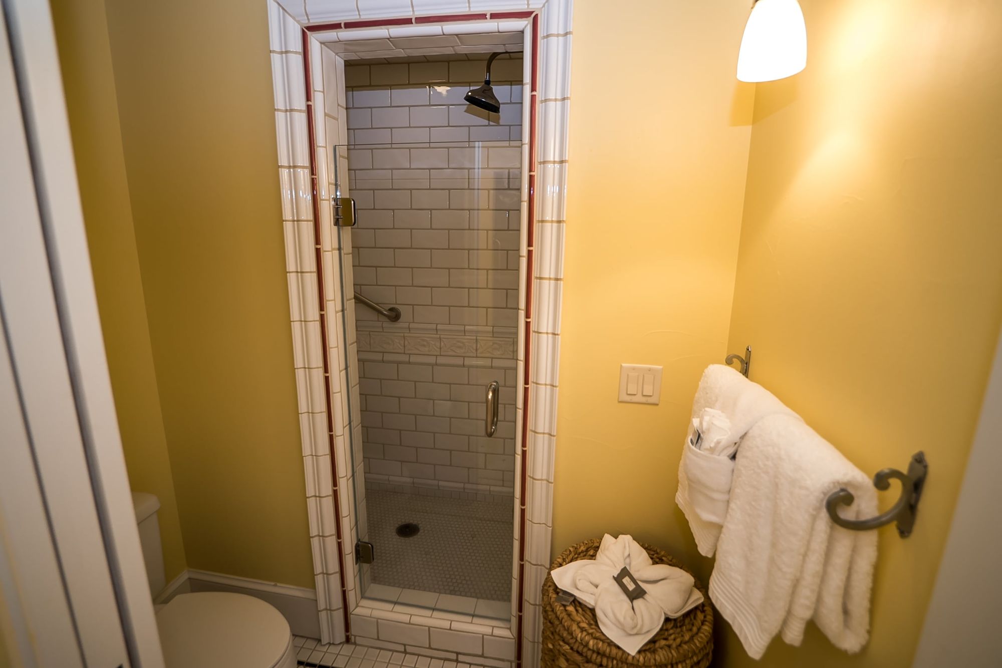 Walk-in shower, toilet, and white towels hanging on a rack