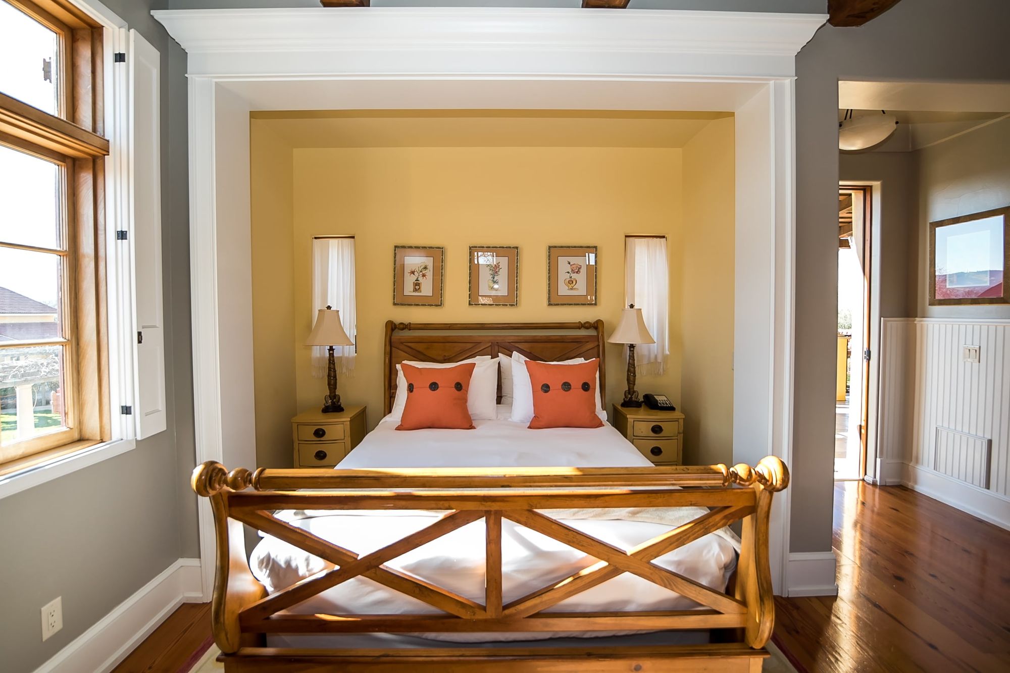 Sleigh bed made up with white sheets and orange accent pillows