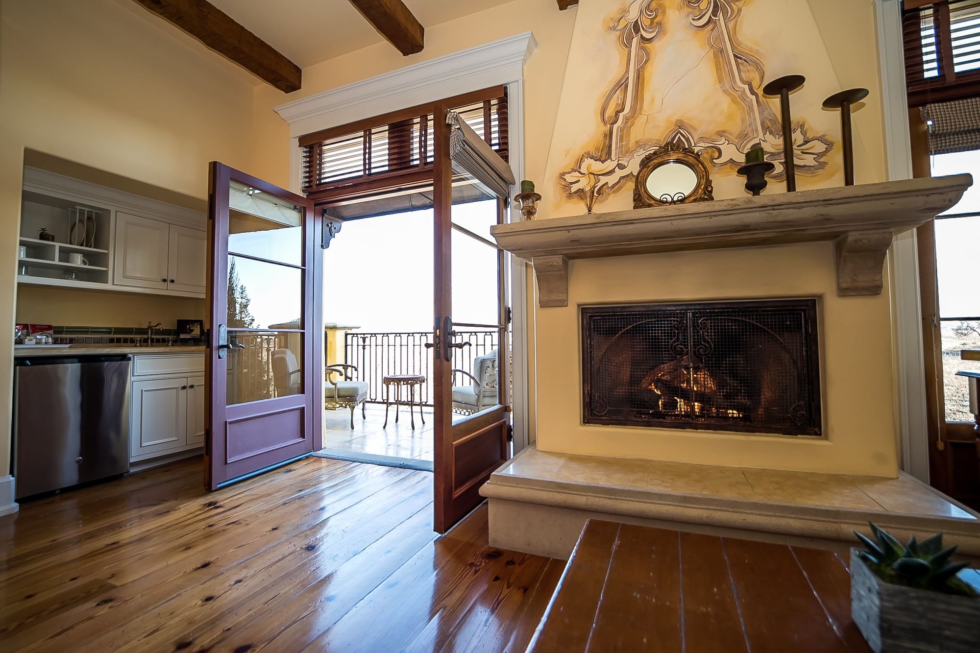Decorative fireplace with French doors open to the patio to the left and the wet bar behind the door