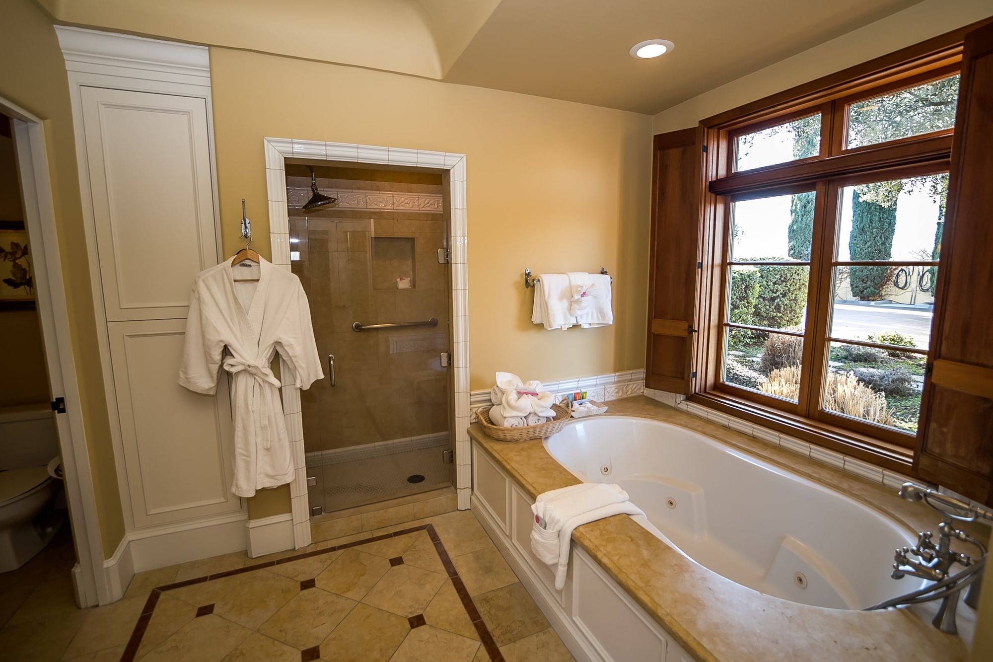 Spa bathtub with walk in shower to the side and a robe hanging on a hook