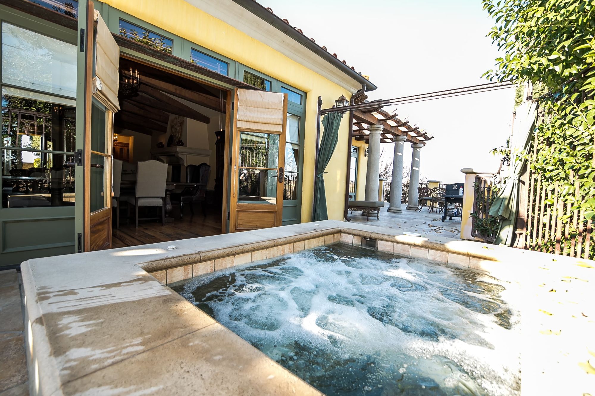 Hot tub bubbling on patio outside open French doors
